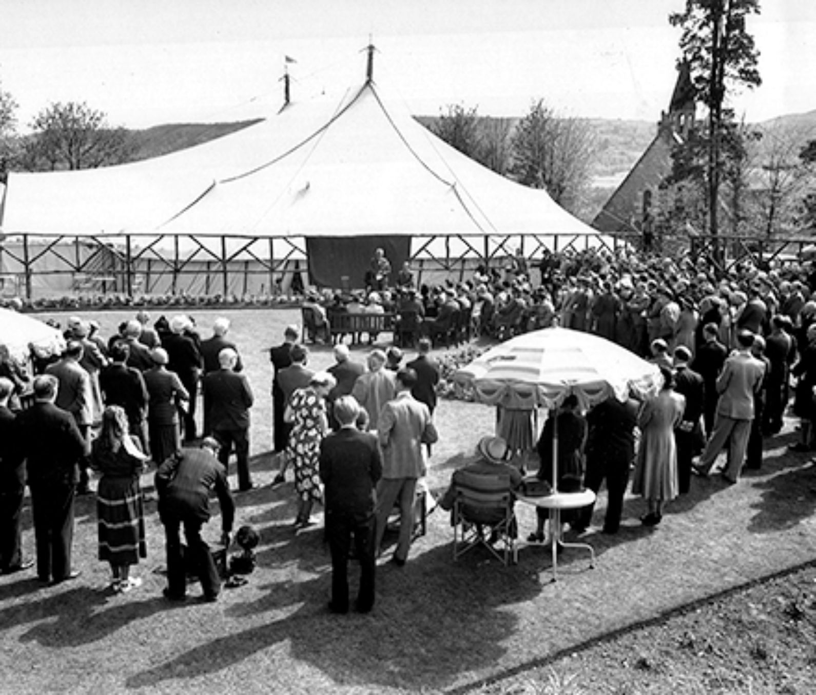 A black and white image from the opening of the theatre in 1951, a large group of people crowd around a tent in a field