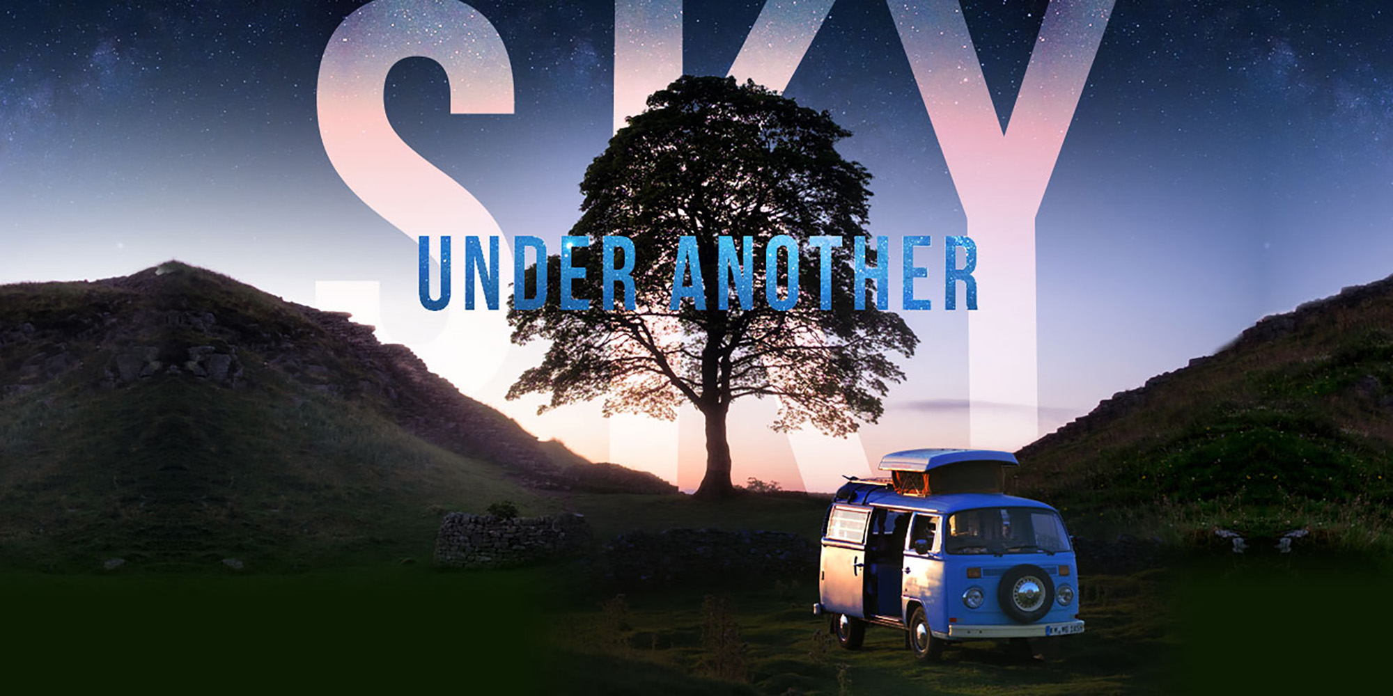 Blue camper van next to a tree in front of some hills under the night sky