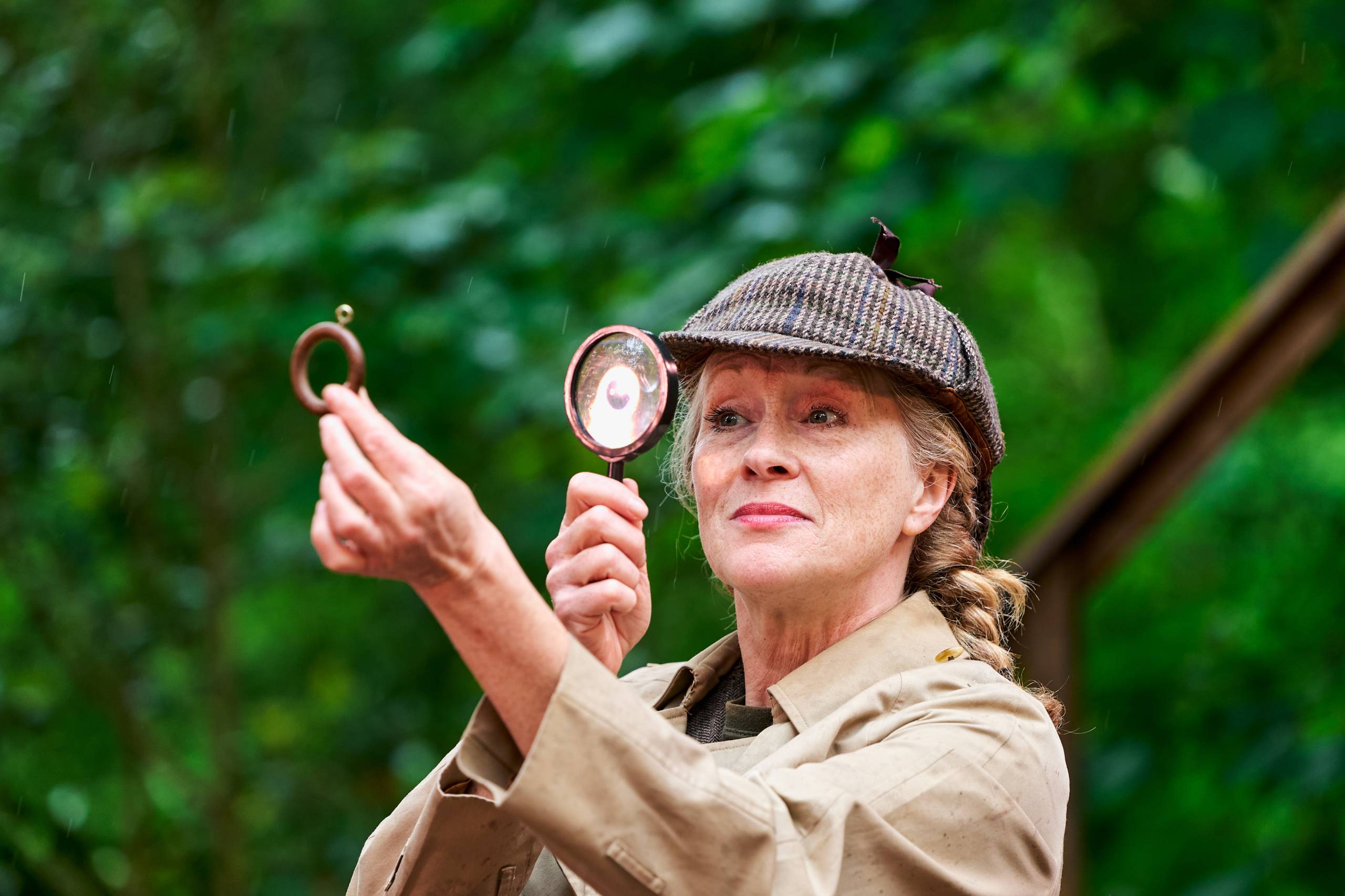 A woman looking as a curtain hook through a magnifying glass.