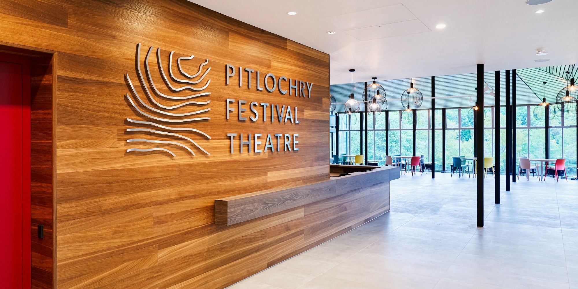 An image of a logo and the text 'Pitlochry Festival Theatre' to the right with some tables and chairs in the background.