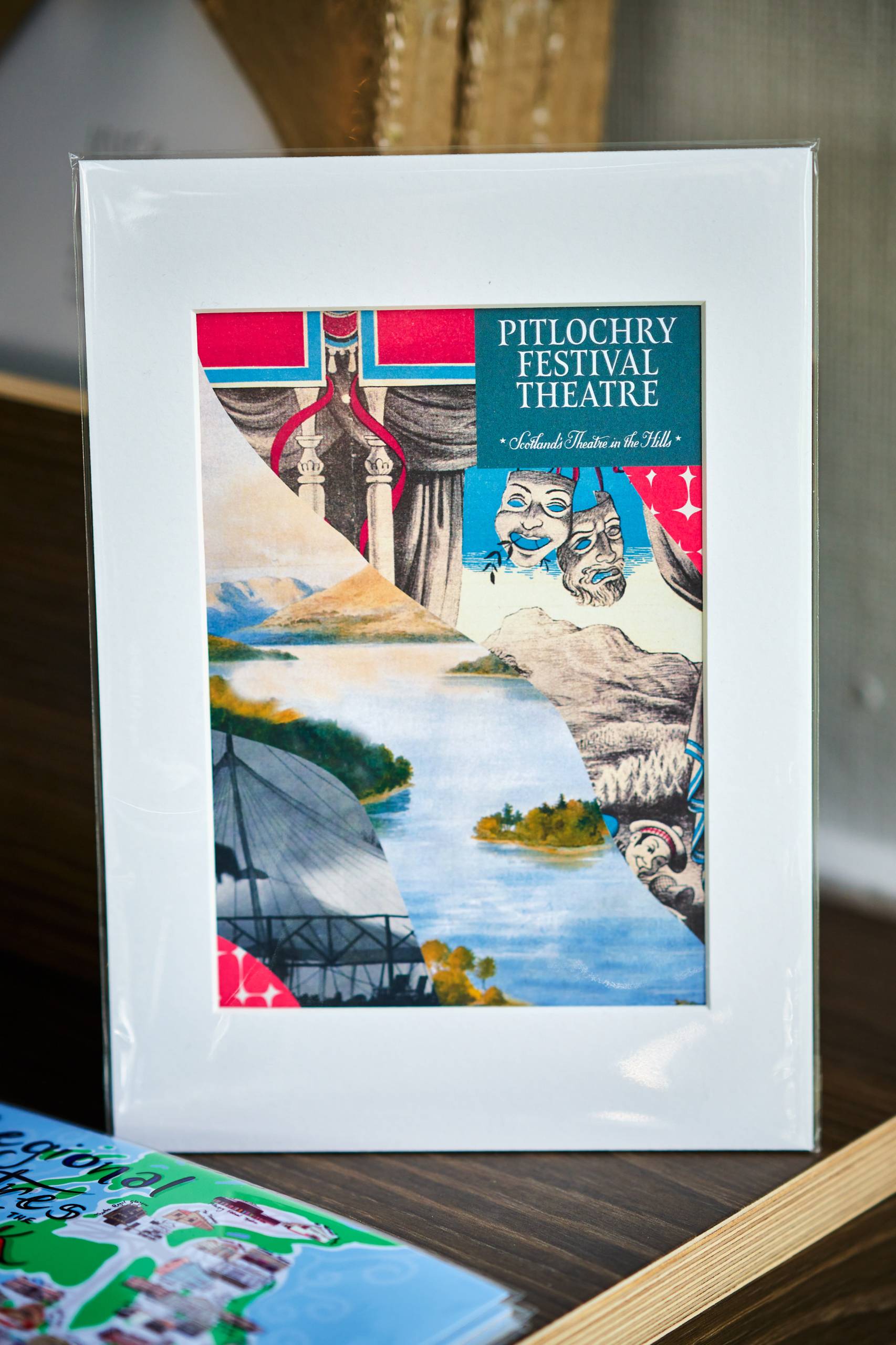 A card sat on a table with the words pitlochry festival theatre on it as well as the laughing and crying theatre faces