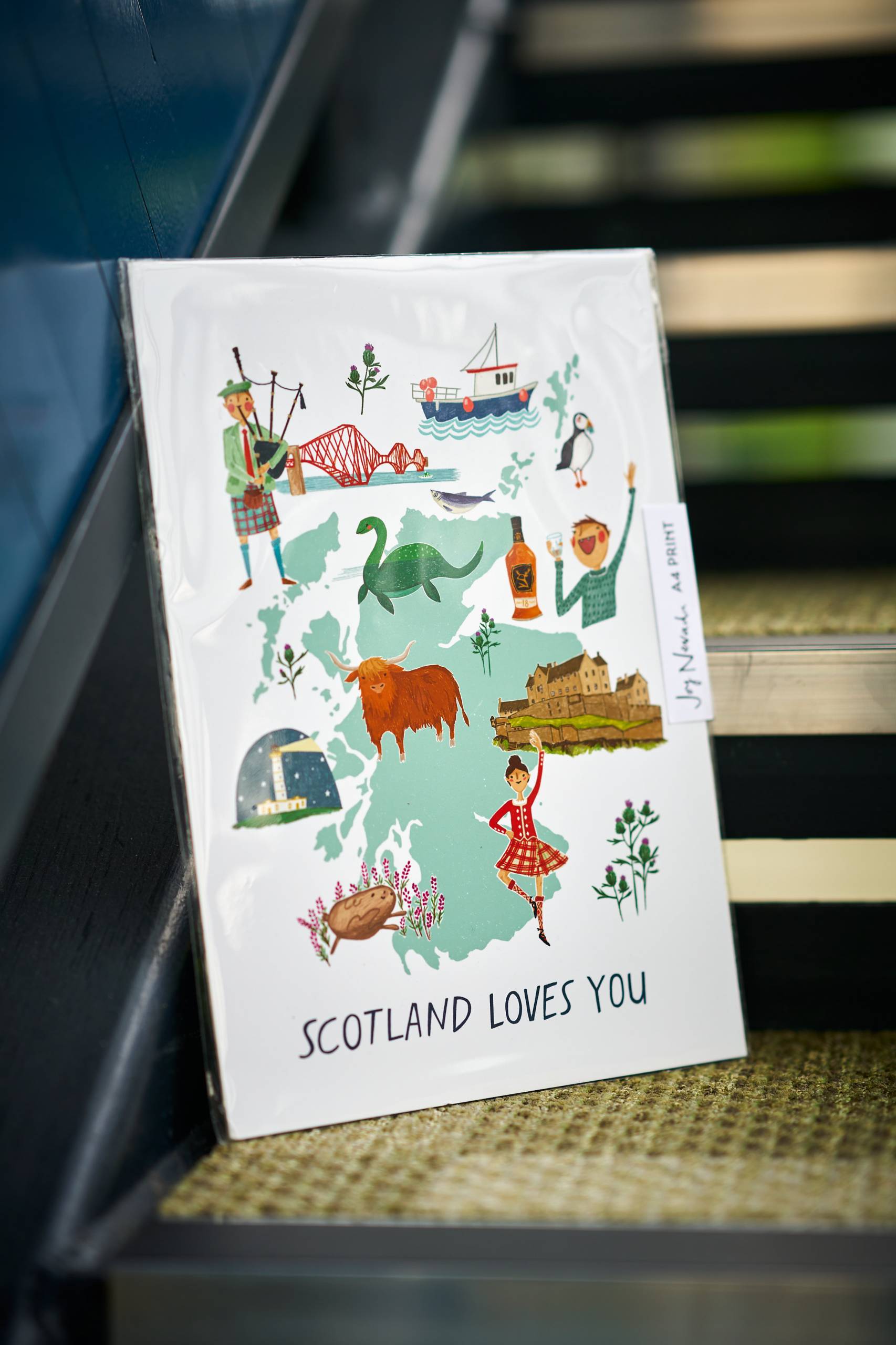 A card with the map of scotland sat on a staircase against a glass panel