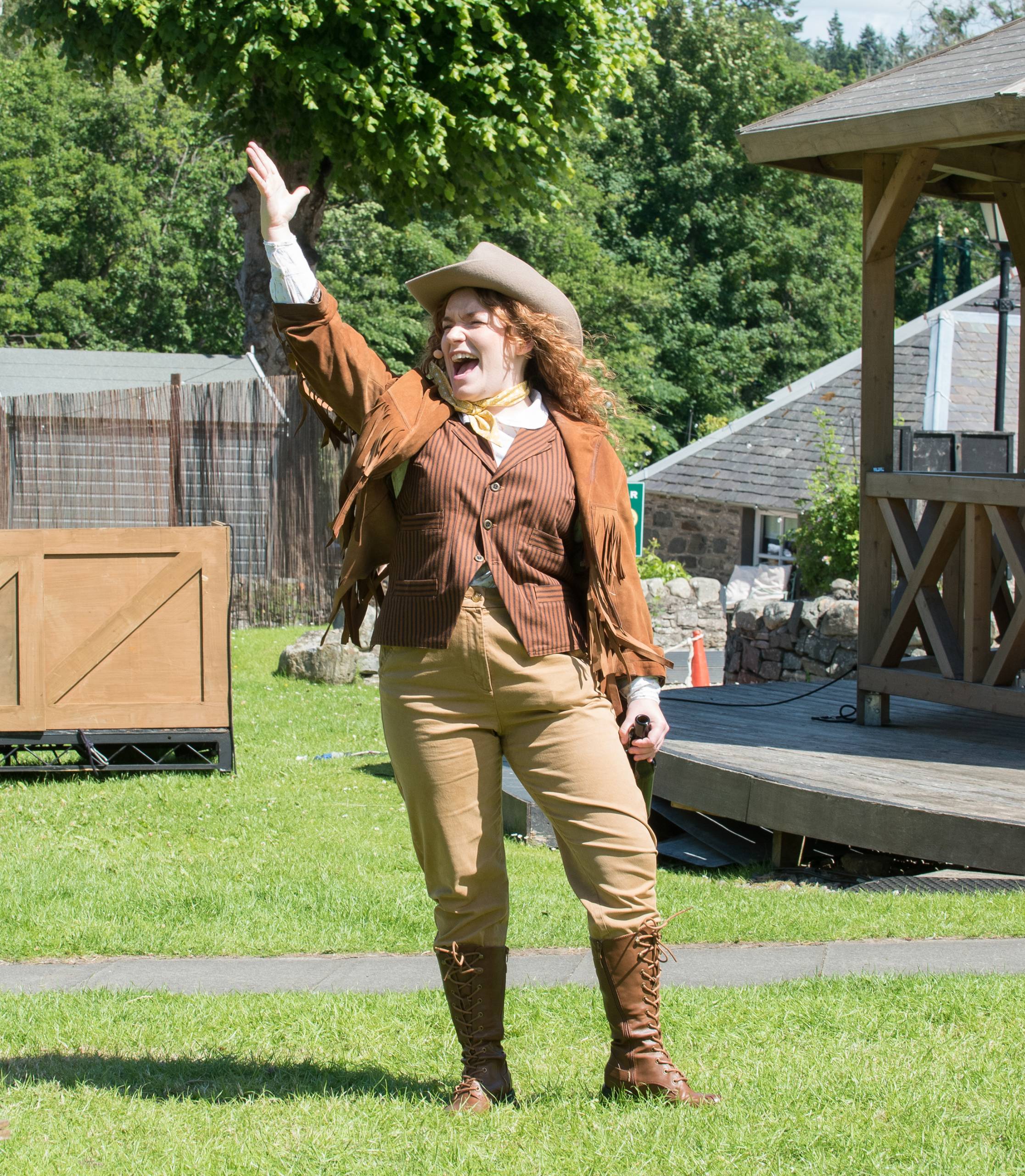 A woman wearing a western outfit with her arm in the air.
