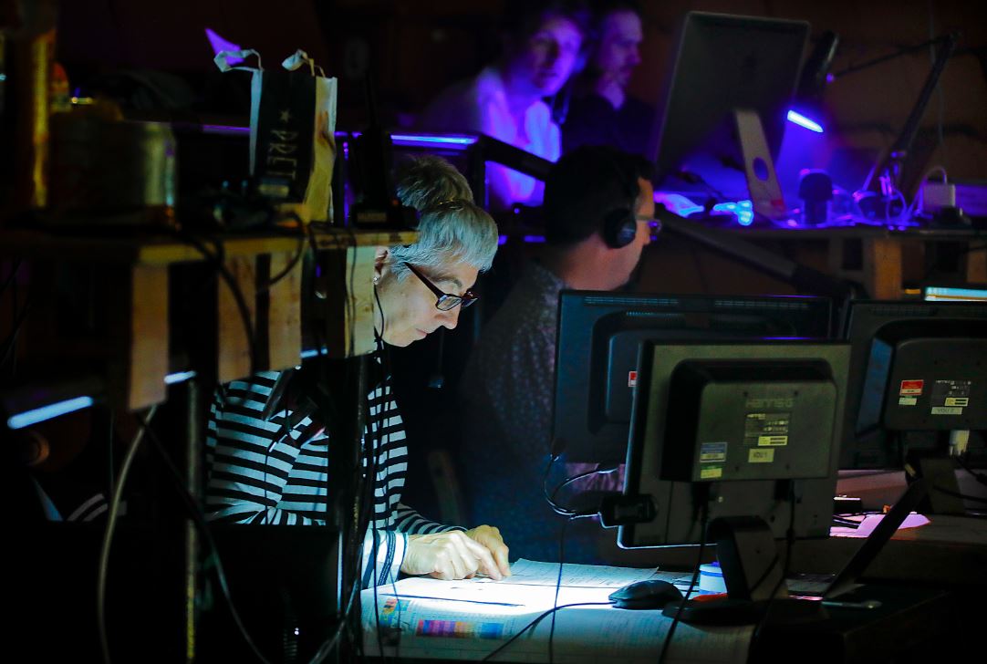 Jo Townsend sitting at a desk in the auditorium looking at several computers.