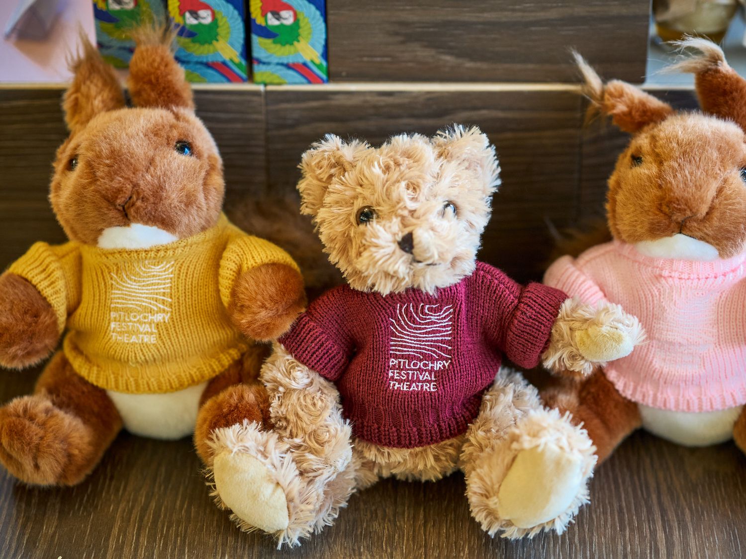 Stuffed toys with knitted jumpers on that have the Pitlochry Festival theatre logo embroidered.